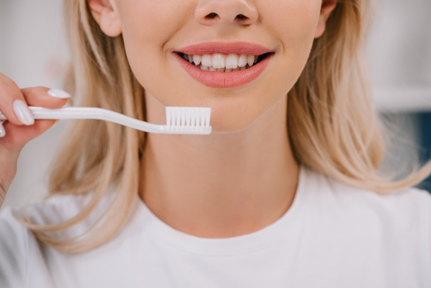 részleges kilátás a mosolygó nő gazdaság fogkefe - Fotó, kép