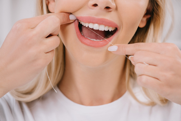 vista recortada de la mujer dientes de hilo dental con hilo dental
 - Foto, Imagen