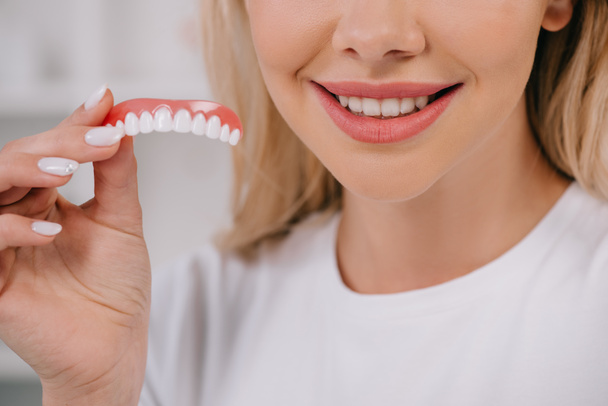 обрізаний вид усміхненої жінки, що тримає покриття зубів
  - Фото, зображення