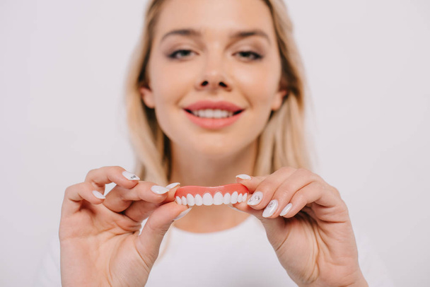 красива усміхнена жінка тримає покриття зубів і дивиться на камеру ізольовано на білому
 - Фото, зображення