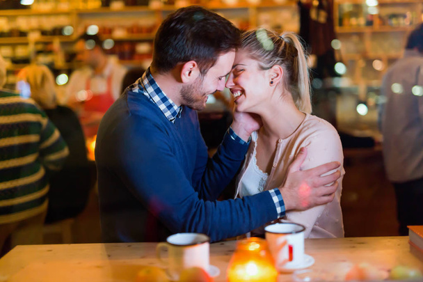 Happy attractive couple kissing at bar having date - Фото, изображение