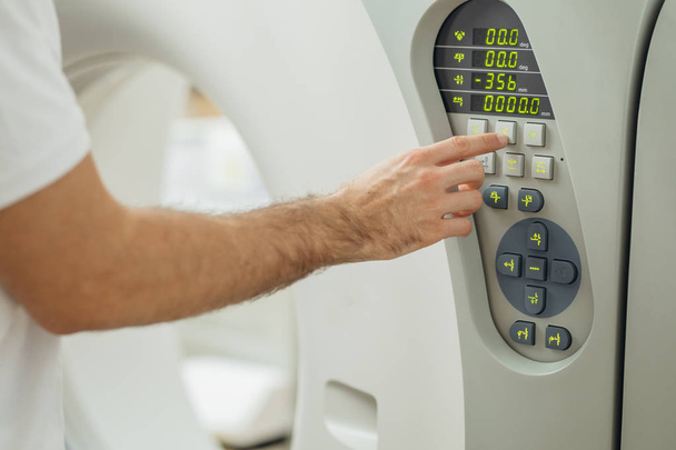 Mãos de um técnico médico pressionando botões no scanner CT
. - Foto, Imagem
