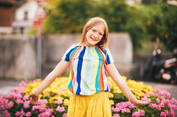 Summer portrait of pretty kid kid girl posing outdoors, wearing yellow skirt and colorful blouse - Foto, imagen