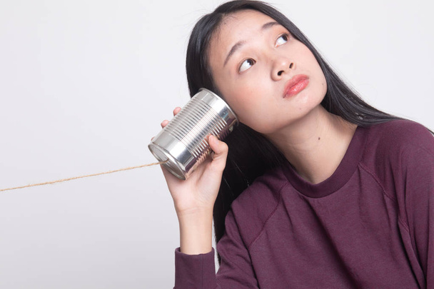 Young Asian woman with tin can phone on white background - Foto, immagini