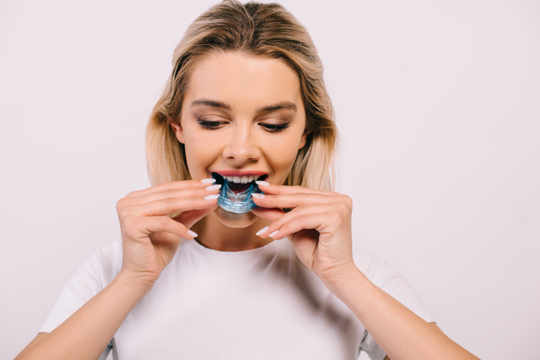 beautiful woman putting on orthodontic trainer dental braces isolated on white - Photo, Image