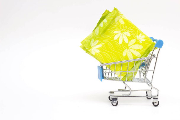 Female pads in a shopping trolley on a white background, personal hygiene shopping concept, close-up, copy space - Foto, afbeelding