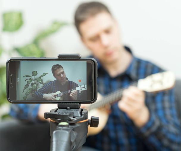 Un bel homme enregistrant une chanson. Concept de vlogging
. - Photo, image