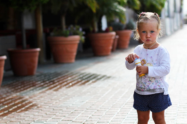 kleines süßes Mädchen mit lustiger Fratze auf der Straße - Foto, Bild
