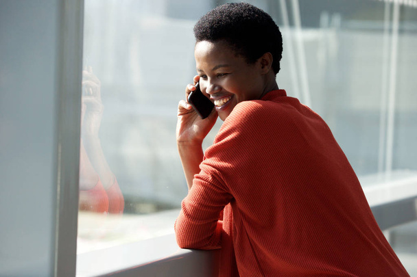 クローズ アップ ウィンドウで携帯電話で話している幸せのアフリカの女性の肖像画 - 写真・画像