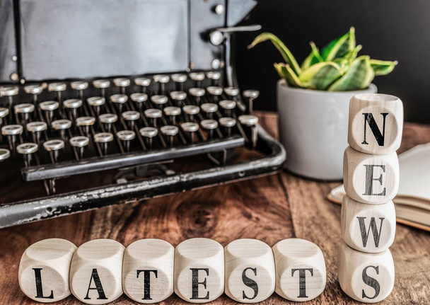 words LATEST NEWS on wooden blocks with vintage typewriter and potted plant in background - Photo, Image