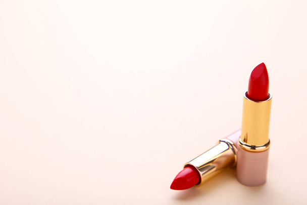 Two red lipsticks on beige background. Cosmetic - Fotó, kép