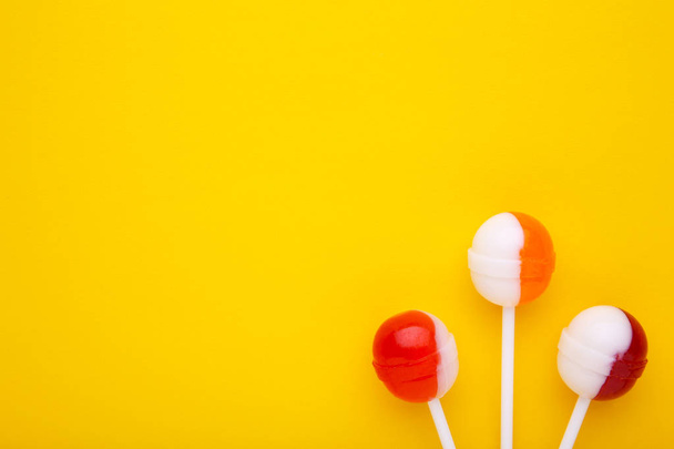 Colorful lollipops on yellow background. sweet candy concept - Fotografie, Obrázek