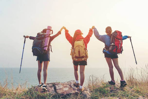 Group friend team asian young women of hikers walking adventure with backpack on a mountain at sunset. Traveler life going trip camping outdoors. Travel and Vacations Concep - Zdjęcie, obraz