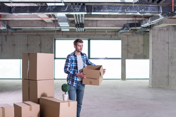 portrait of young businessman on construction site checking documents and business workflow with cardboard boxes around him in new startup office - Photo, Image