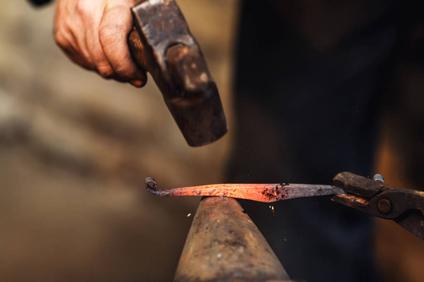 Schmied schmiedet kunstvoll heißes Metall auf dem Amboss. - Foto, Bild
