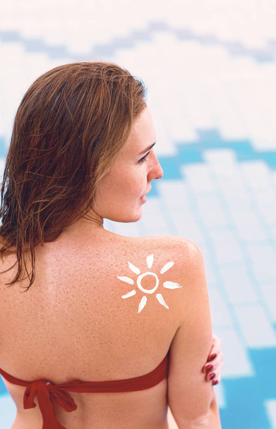 Woman With Suntan Lotion At The Beach In Form Of The Sun. Portrait Of Female With the Drawn Sun On a Shoulder On The Pool - Foto, Imagem