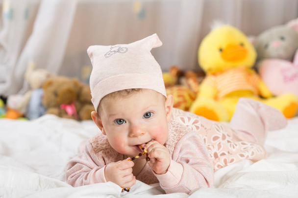 Красива новонароджена дівчинка з капелюхом, лежить у ліжку і посміхається
. - Фото, зображення