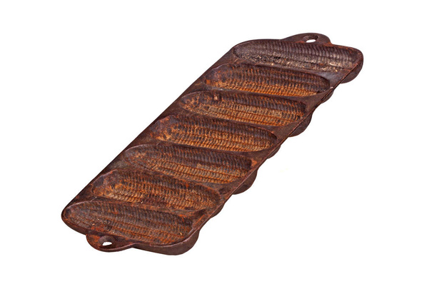 Sartén vieja, oxidada, de hierro fundido para hornear palitos de pan de maíz en forma de maíz en la mazorca aislada sobre un fondo blanco
 - Foto, imagen