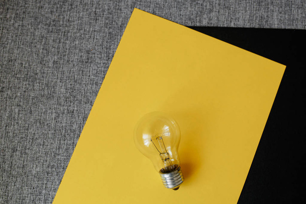 light bulb on the yellow and black sheet background - Foto, afbeelding