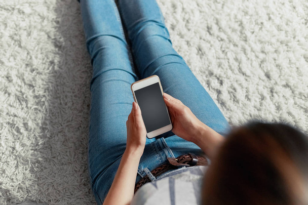 Young woman holding credit card and using phone sitting on floor. Payment.  Online shopping concept.Concept of blogging. Modern technologies Top view. - Photo, Image