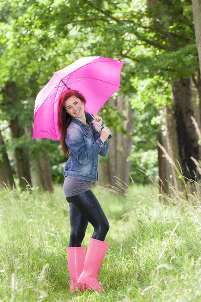 Mujer con botas de goma con paraguas en la naturaleza de primavera
 - Foto, Imagen