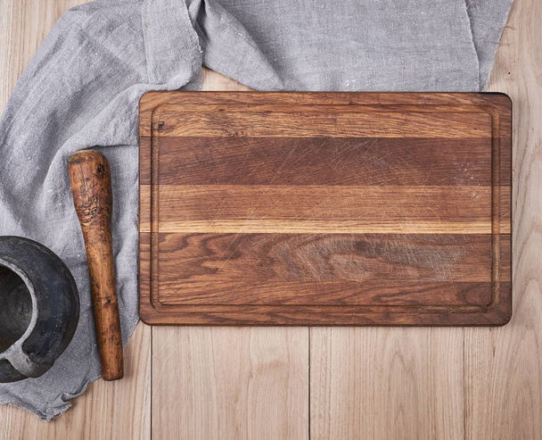 Placa de corte de cozinha de madeira velha vazia e uma toalha cinza em uma mesa, a vista do topo
 - Foto, Imagem