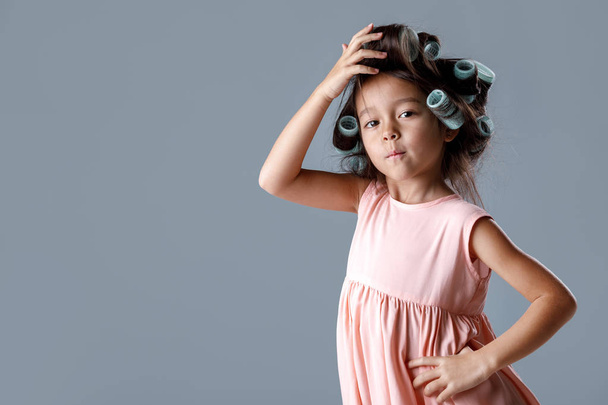cute little child girl in pink dress and hair curlers - Foto, immagini
