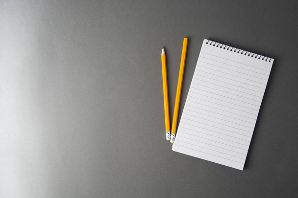 Notepad or notebook with pencil on gray background. Concept for education, business - 写真・画像