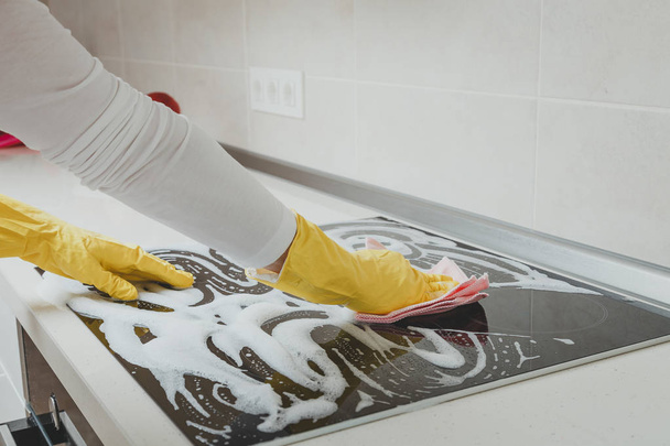 Housewife cleaning an induction plate, closeup shot - Fotografie, Obrázek