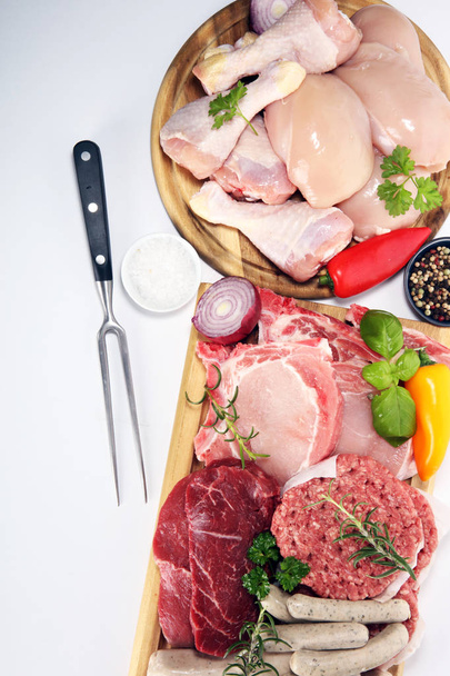 rauw vlees. Verschillende soorten rauwe varkensvlees, kip en rundvlees met specerijen en kruiden en worstjes - Foto, afbeelding