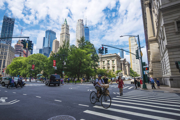 New York City, USA - 27. Juli 2018: Wolkenkratzer in der Innenstadt und im Rathauspark mit einem Radfahrer und Menschen in Manhattan, New York City, USA - Foto, Bild