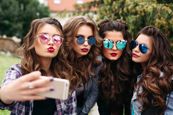Modieuze dames met kapsel nemen selfie buitenshuis. - Foto, afbeelding