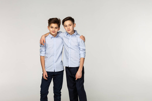 Young brothers in blue shirts hugging in the studio - Фото, зображення