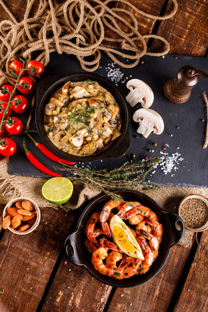 Fried large shrimp in tomato sauce with olive oil,Mushrooms in cream sauce, julienne, champignon, products for cooking on wooden table background - Photo, Image