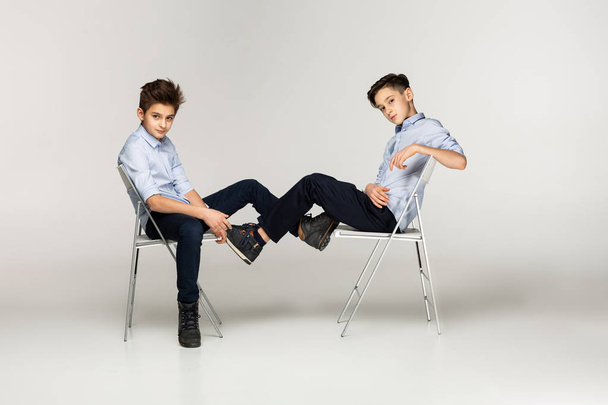 椅子に座っている青いシャツで二人の少年のティーンエイ ジャー - 写真・画像