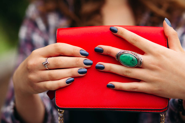 Unrecognizable woman with dark nails holding red handbag. - Photo, image