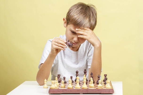 Niño jugando al ajedrez. Niño mirando tablero de ajedrez y pensando en su estrategia
. - Foto, Imagen