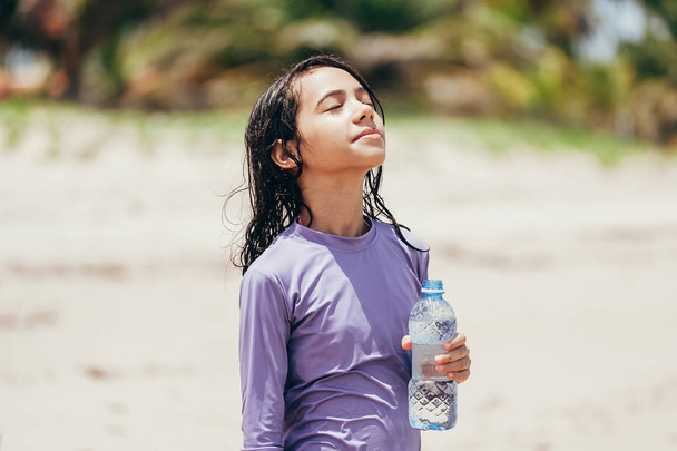 Portrait of little girl drinking water on the beach - Foto, Imagem