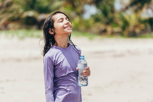 Portrait de petite fille buvant de l'eau sur la plage
 - Photo, image