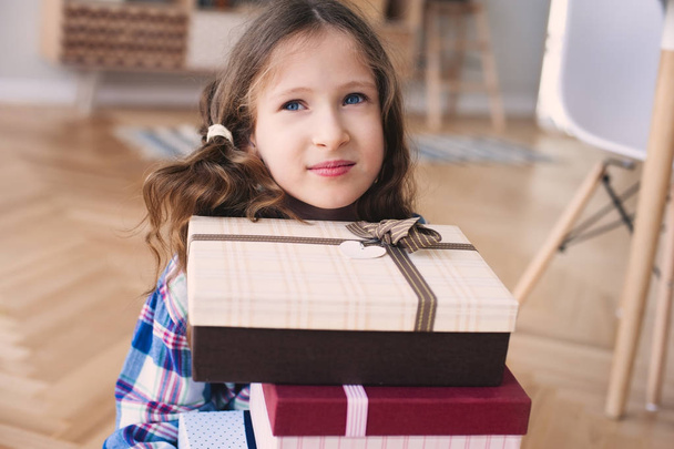happy kid girl preparing or getting many gifts for birthday. Child with stack of gifts at home - Foto, Imagem