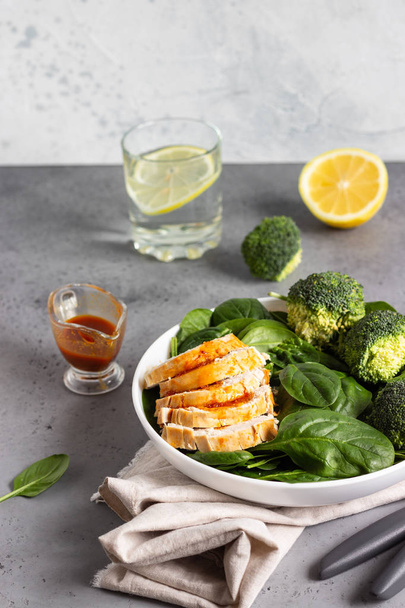 Chicken breast with spinach, broccoli and citrus dressing on a white plate. Grey concrete background. Copy space. Healthy diet lunch or dinner. Keto diet. - Foto, Imagem