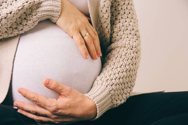 Bílá těhotná žena drží břicho s oběma rukama detailním - Fotografie, Obrázek
