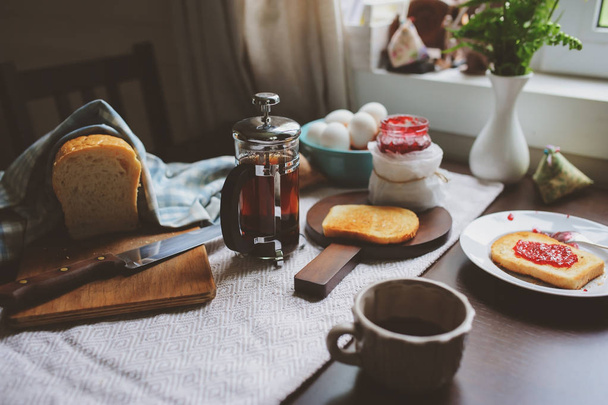 country cottage kitchen with breakfast on wooden table. Toast with jam, farm eggs and coffee - Фото, зображення