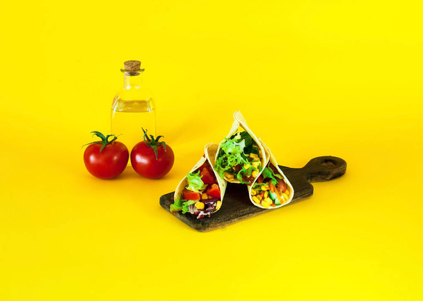 Plato tradicional de la cocina mexicana. Tacos de tortilla de maíz con relleno vegetal sobre fondo amarillo
. - Foto, imagen
