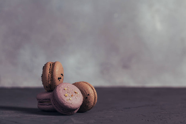 Heap of sweet french macarons on grey concrete background. Pastel colored macaroons cookies. Food, culinary, bakery and cooking concept - Photo, image