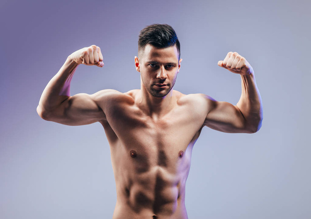 Handsome strong bodybuilder athletic man flexing his muscles. Sport concept - Foto, Bild