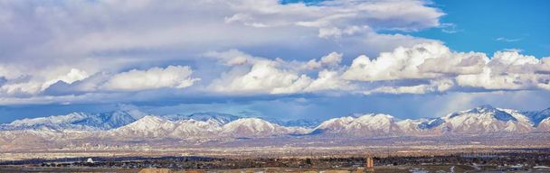 Zimowe Panoramic view śniegu ograniczona Wasatch Front skaliste góry, doliny wielkiego jeziora słonego i Cloudscape od autostrady Bacchus. Utah, Stany Zjednoczone Ameryki. - Zdjęcie, obraz