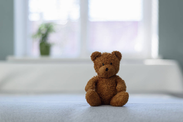 Plush teddy bear toy on white bed - Фото, изображение