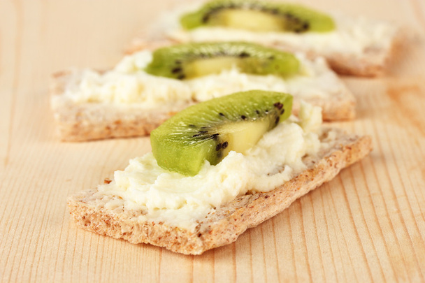 Tasty canapes with cheese and kiwi, on wooden background - Zdjęcie, obraz