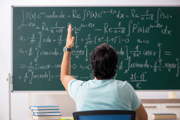 Νεαρός φοιτητής αρσενικό μαθηματικός μπροστά από μαυροπίνακα  - Φωτογραφία, εικόνα